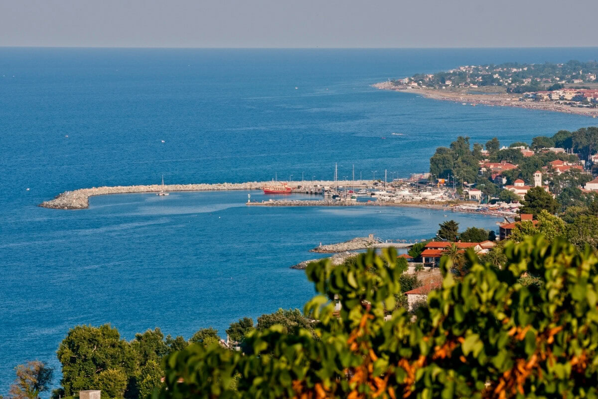 Egy festői kikötő és tengerparti táj a Jasi Tours utazási szolgáltatásokhoz, tengerparti nyaralás, hajóutak és mediterrán környezet.